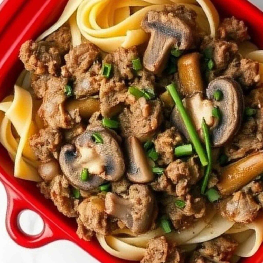 ground beef swirled with noodles and sauce in a red baking dish