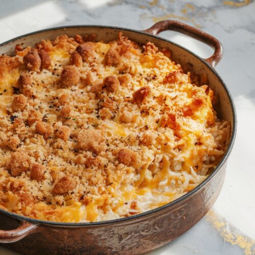 A cheesy, bubbly chicken and rice casserole with a crispy breadcrumb topping, served in a rustic baking dish.