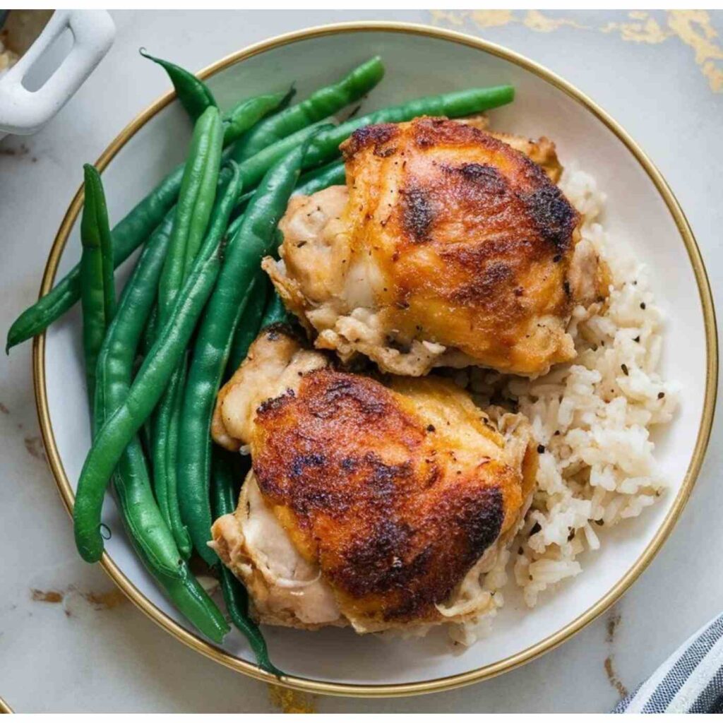 Plate of baked boneless chicken thighs over rice with a side of green beans.