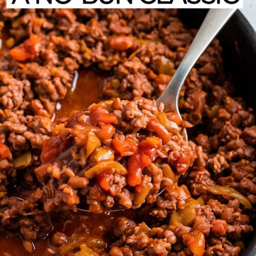 A skillet filled with saucy, keto-friendly sloppy joe beef, with a spoon scooping up a portion. The background includes a small bowl of sugar-free ketchup. Large, bold text overlay: 'Keto Sloppy Joe Skillet - A No-Bun Classic'