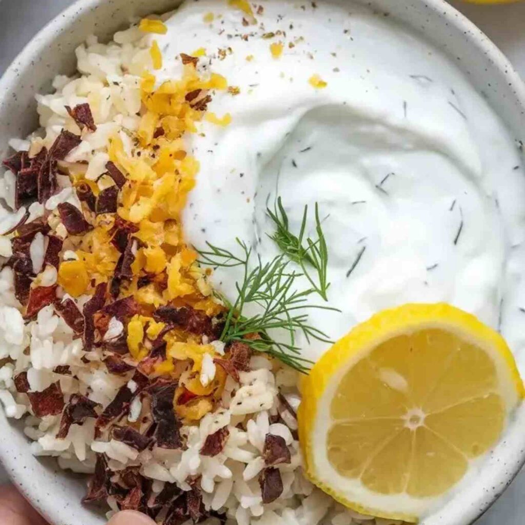 A bowl of tangy yogurt sauce. The sauce is creamy and smooth, with a hint of texture from minced garlic.