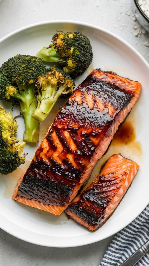 a blackened salmon filet with teriyaki sauce and baked broccoli