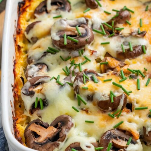 a baked casserole with Swiss cheese melted over mushrooms, melted cheese on top, and garnished with chopped chives