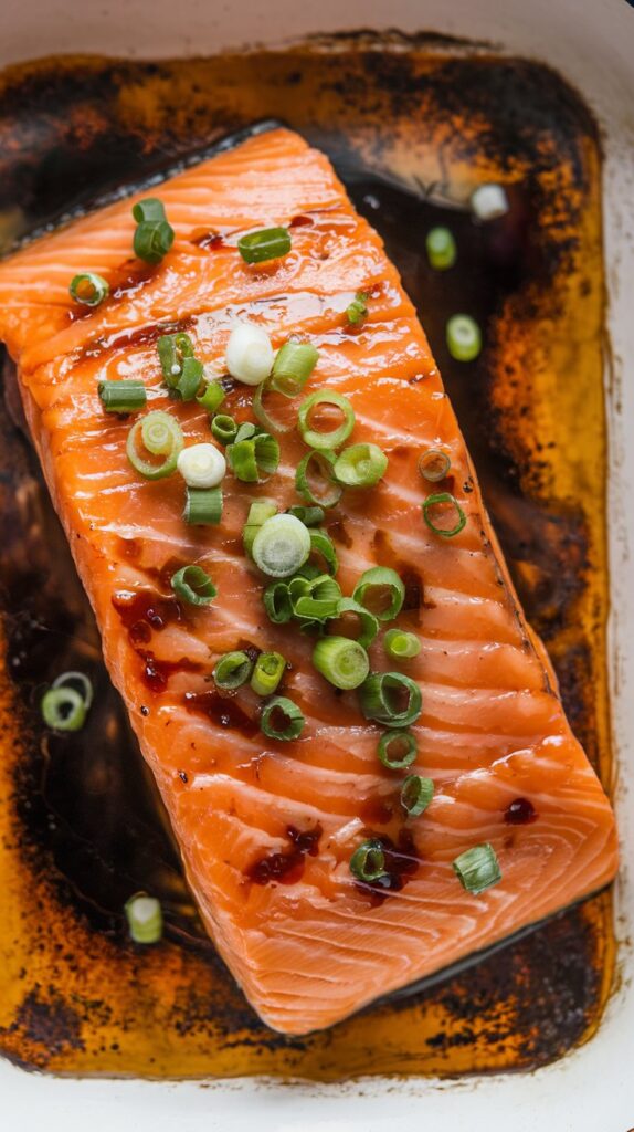 top view of Soy Ginger Marinated Baked Salmon on a plate garnished with green onion