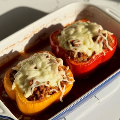Two stuffed bell peppers filled with ground beef and rice, topped with melted cheese.