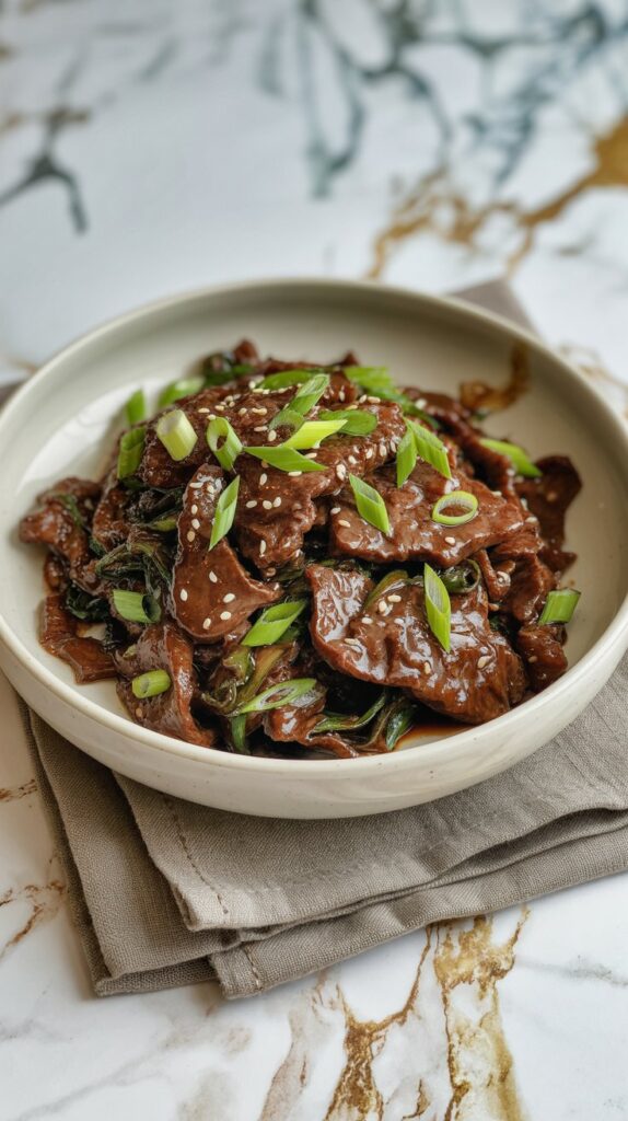 a bowl of beef steak sprinkled with sesame seeds and garnished with scallions