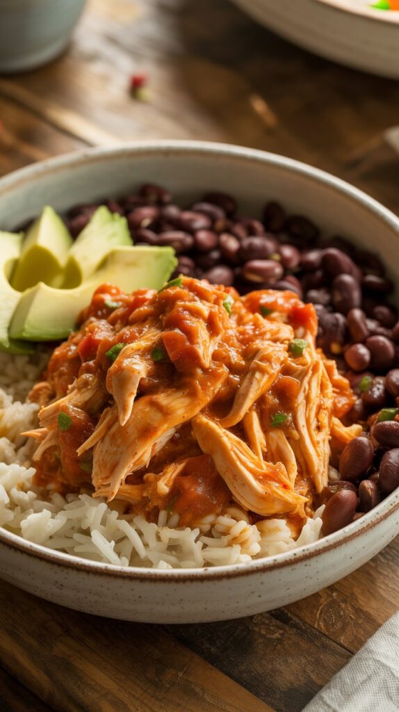 a bowl of rice with beans, avocado and spicy chicken