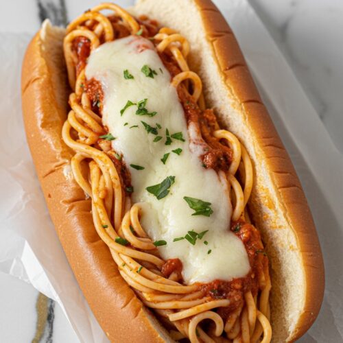 a spaghetti sandwich served in a soft, toasted hot dog bun, filled with cheesy marinara spaghetti and lightly melted mozzarella,