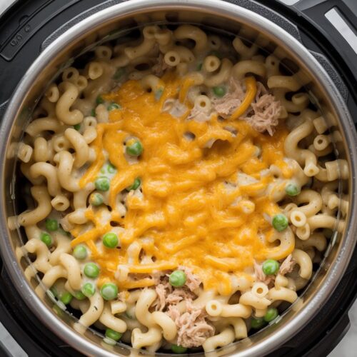 An Instant Pot liner filled with elbow macaroni, tuna, peas, and melted cheddar cheese in a creamy sauce, viewed from a top-down angle.