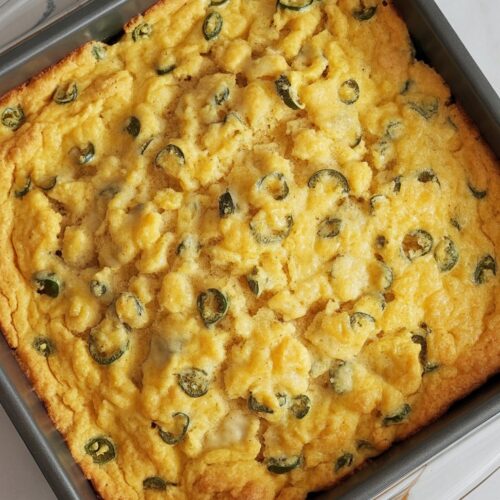 a pan of baked cornbread with pieces of jalapeno peeking through