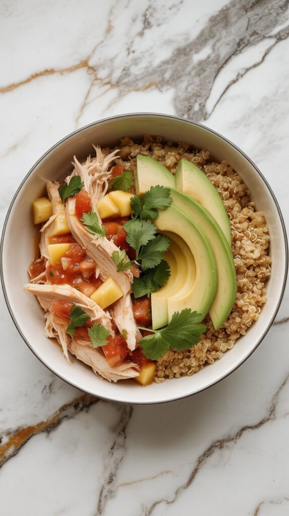 Pineapple salsa chicken served over quinoa with avocado and cilantro garnish