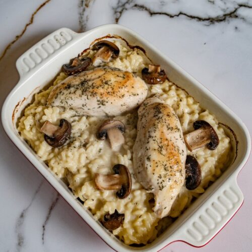 baked chicken and mushroom risotto in a small white baking dish