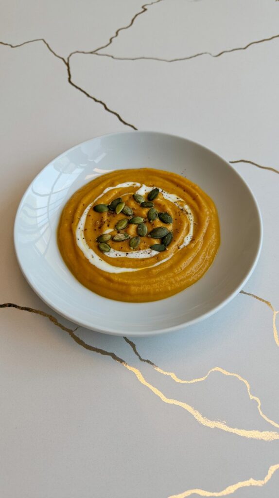 Thick and smooth bowl of creamy pumpkin soup roasted peptios