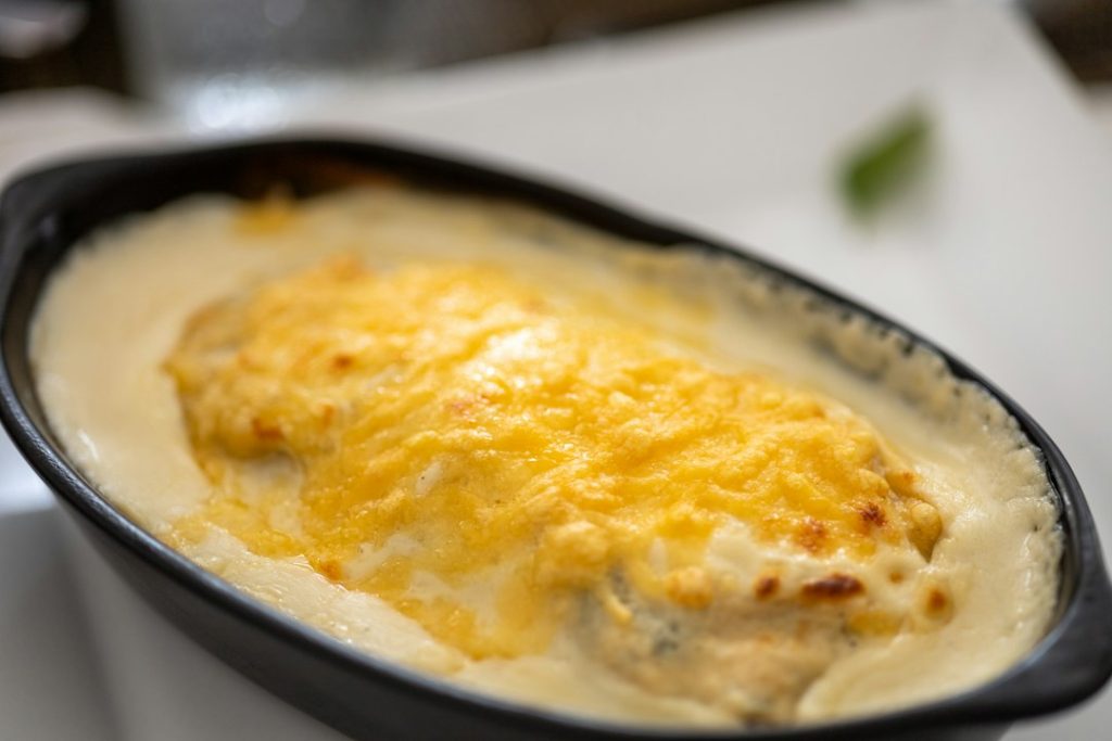 Baked chicken casserole with a golden melted cheese top in an oval dish