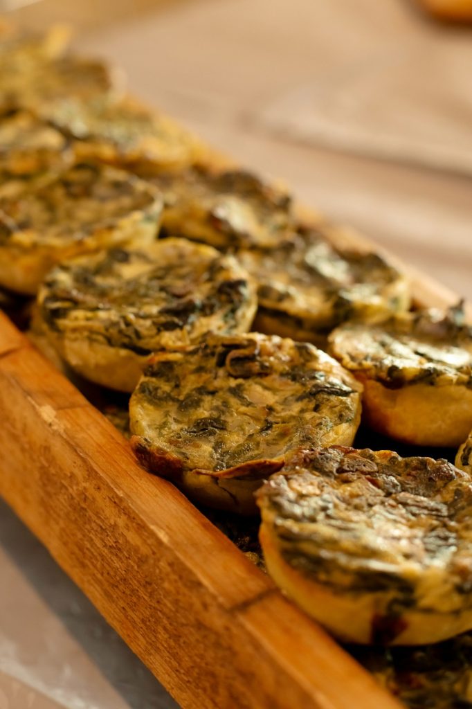 Baked mini egg bites with spinach lined up on a wooden serving tray