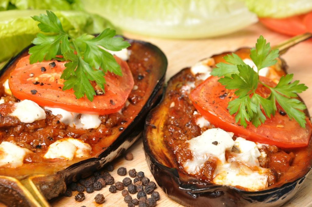 Baked vegetable boats stuffed with meat sauce, topped with melted cheese, tomato slices and parsley