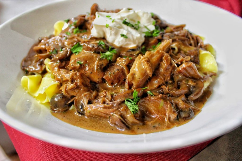 Beef and mushroom stroganoff in a creamy sauce topped with sour cream and parsley