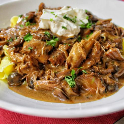 Beef and mushroom stroganoff in a creamy sauce topped with sour cream and parsley