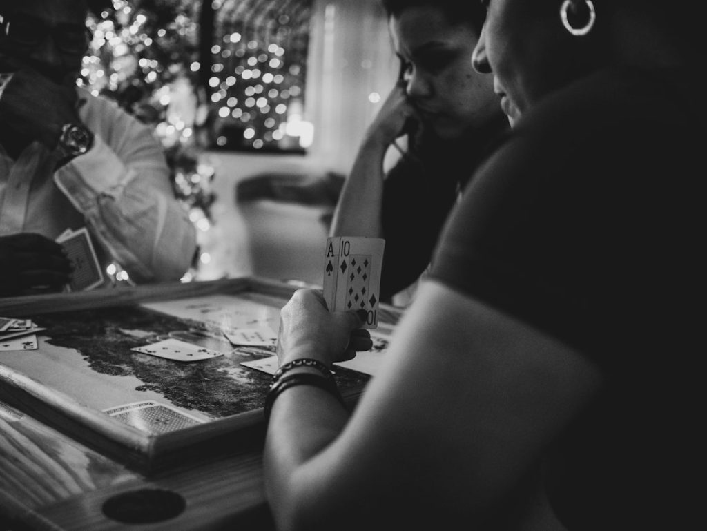 Black and white photo of people gathered around a table playing a card game
