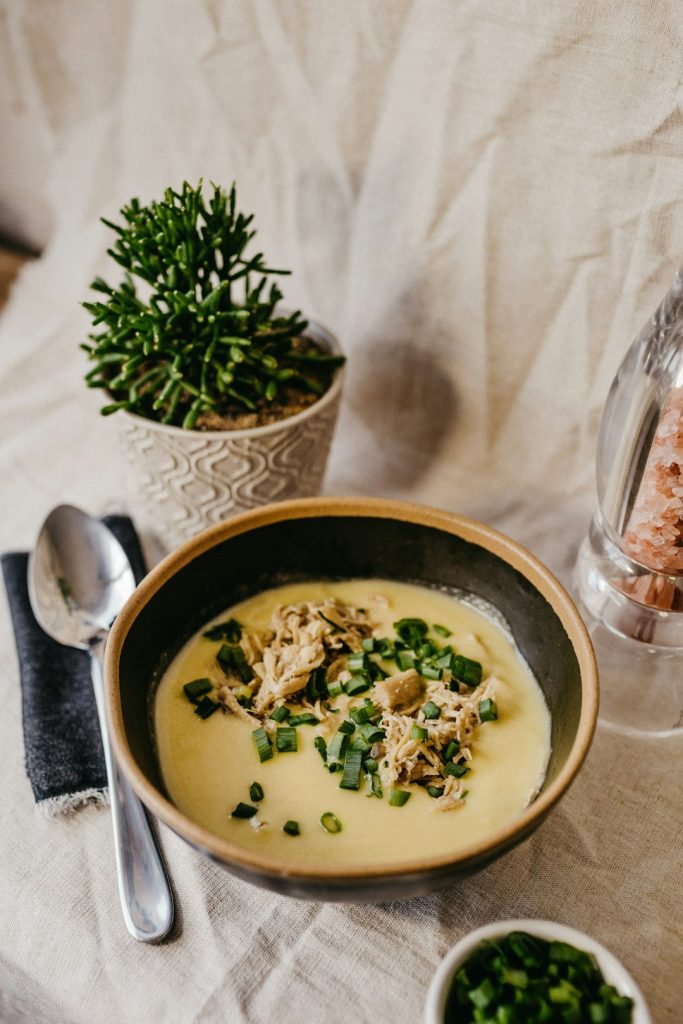 Bowl of creamy potato soup topped with green onions and diced toppings