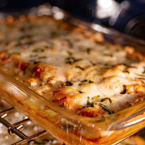 Cheesy casserole baking in a glass dish on an oven rack