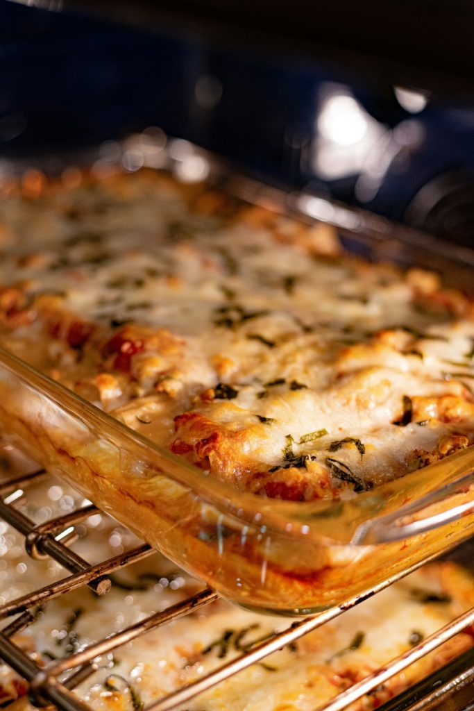 Cheesy casserole baking in a glass dish on an oven rack