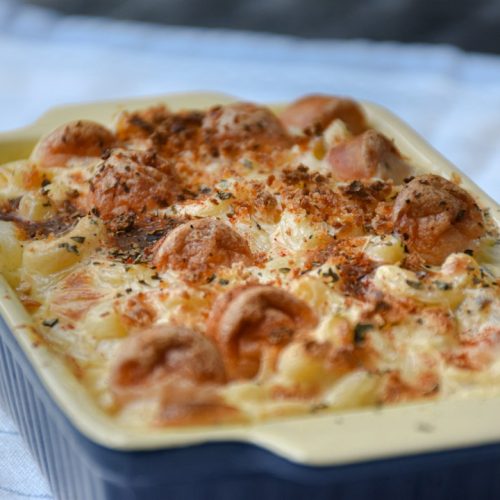 Cheesy salmon pasta bake with a golden top in a blue baking dish