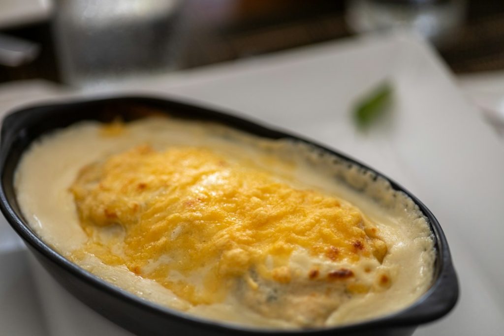 Close-up of a chicken bake with a golden parmesan and cheese crust in an oval dish