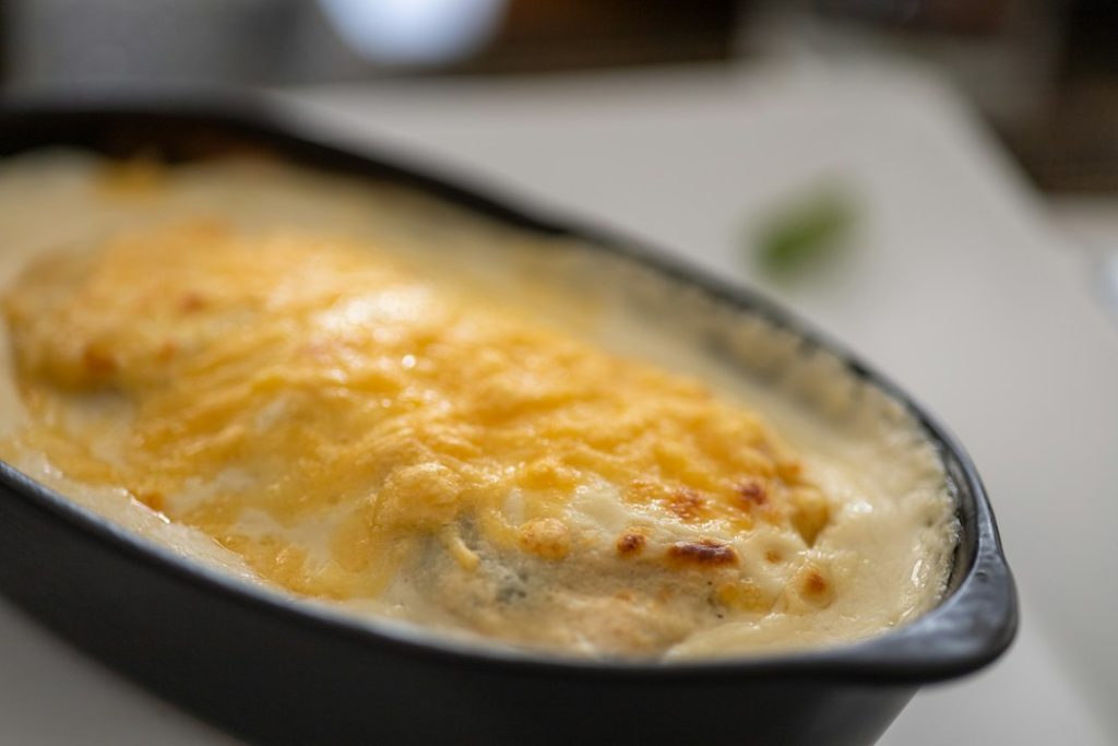 Creamy baked casserole with a bubbling golden cheese topping in a dark oval dish