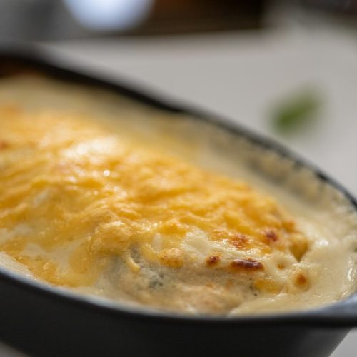 Creamy baked casserole with a bubbling golden cheese topping in a dark oval dish