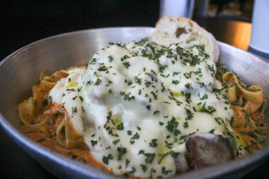Fettuccine in a creamy white sauce with meatballs and chopped parsley