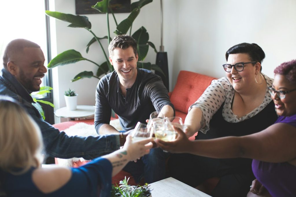 Friends laughing and clinking glasses in a bright living room