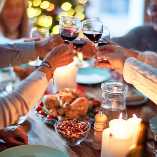 Friends toasting with red wine over a festive candlelit dinner table