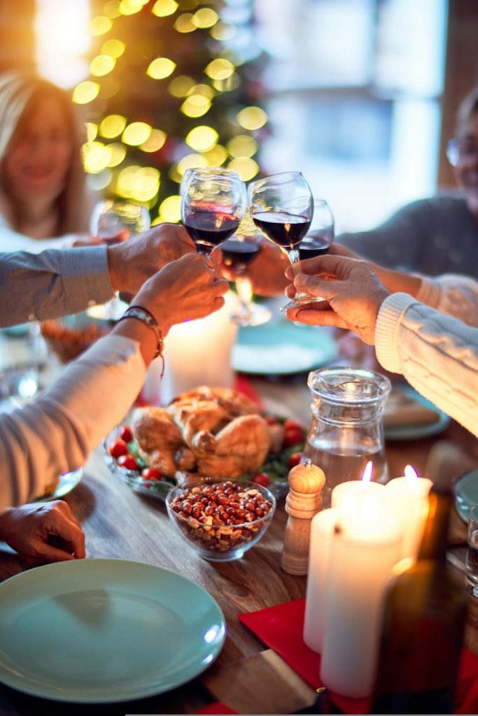 Friends toasting with red wine over a festive candlelit dinner table