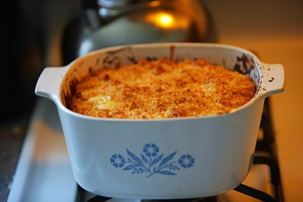 Golden baked casserole with a browned cheese crust in a white casserole dish on the stovetop