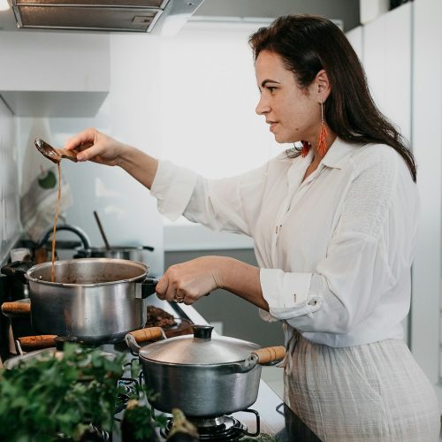 Home cook juggling several pots on the stove with fresh vegetables on the counter