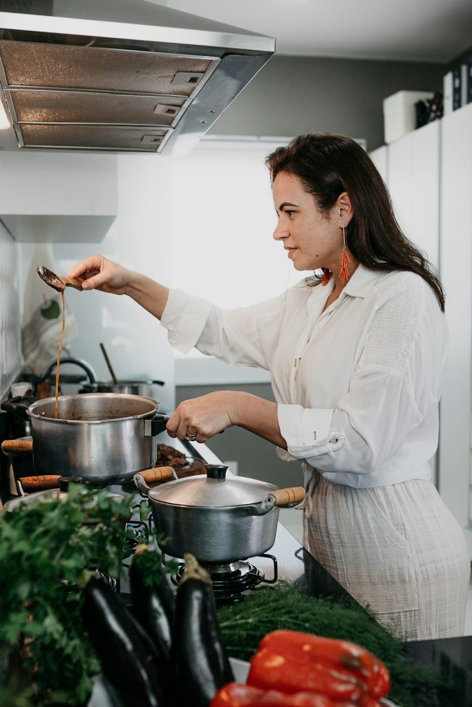 Home cook juggling several pots on the stove with fresh vegetables on the counter