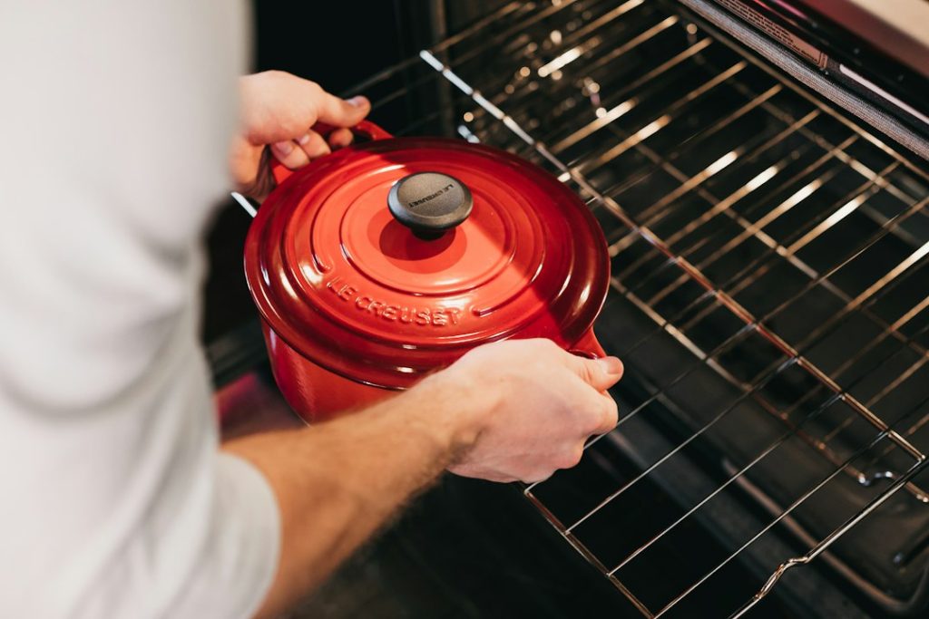 Home cook lifting a red Dutch oven out of the oven
