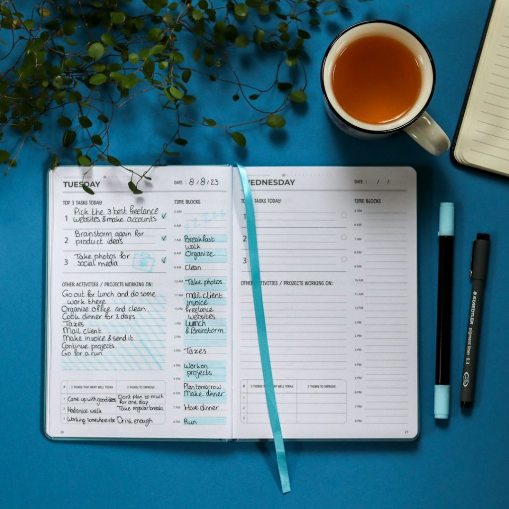 Open daily planner with a busy to-do list next to pens and a cup of tea