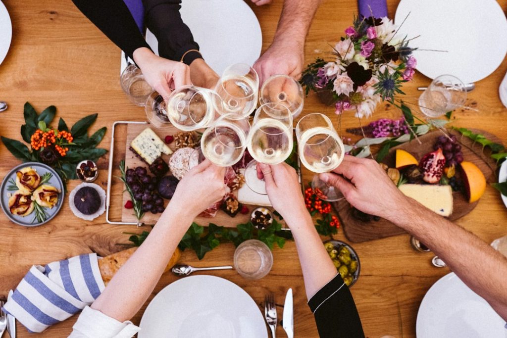 Overhead view of friends toasting with wine glasses above a table of shared food