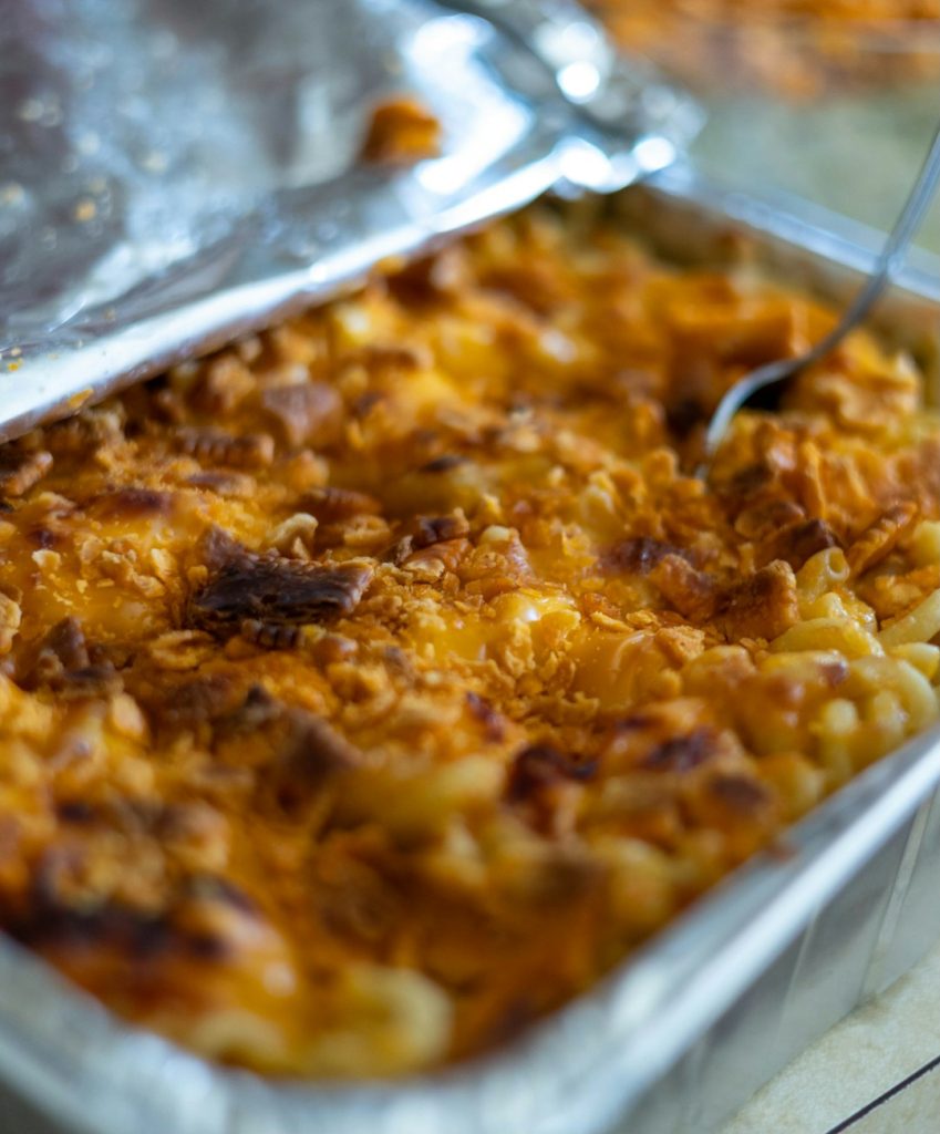 Pan of baked macaroni and cheese with a golden browned top and a serving spoon