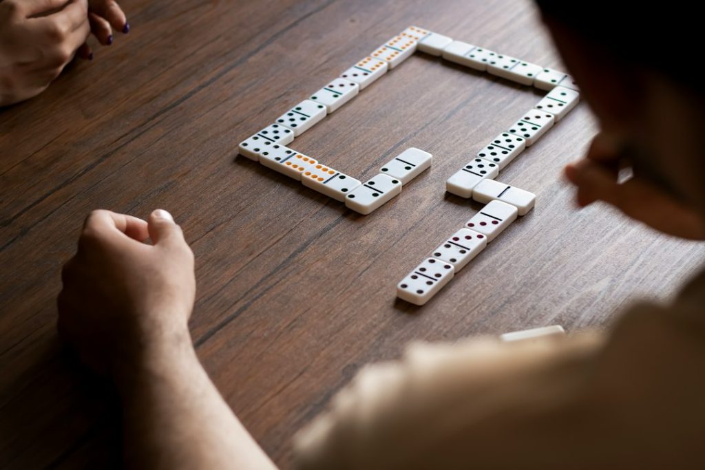 Players laying domino tiles on a wooden table