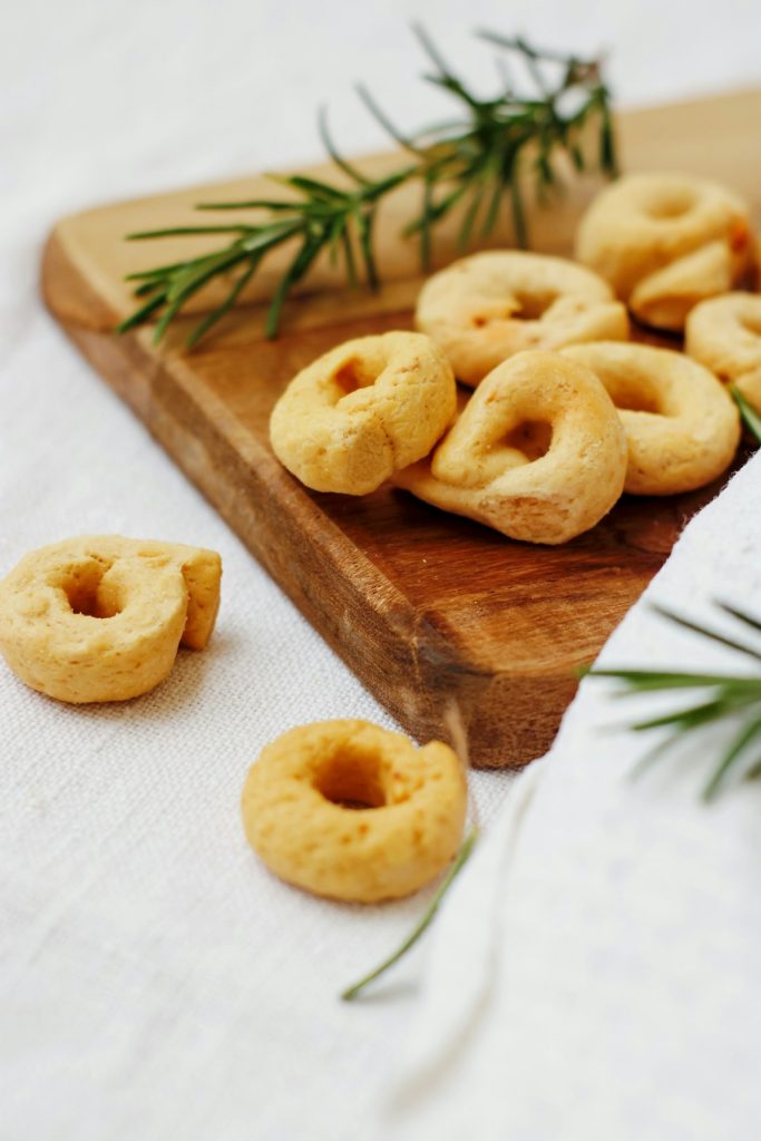 Ring-shaped butter cookies on a wooden board with fresh rosemary sprigs