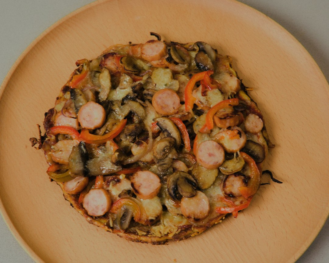 Image of a bubbling keto pizza oozing with cheese and garnished with basil leaves. Text rads "Zucchini Crust -So Crispy!"