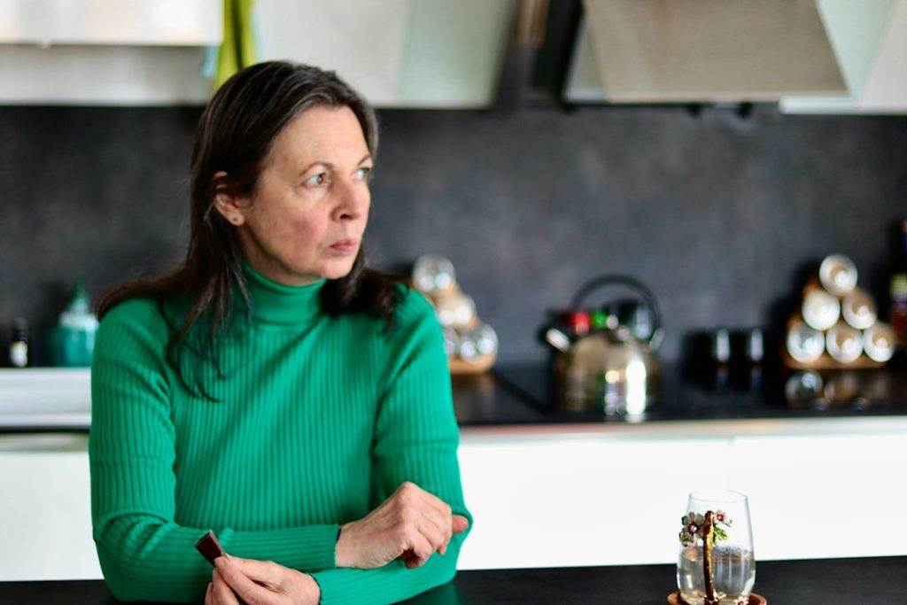 Woman sitting in her kitchen looking tired and thoughtful