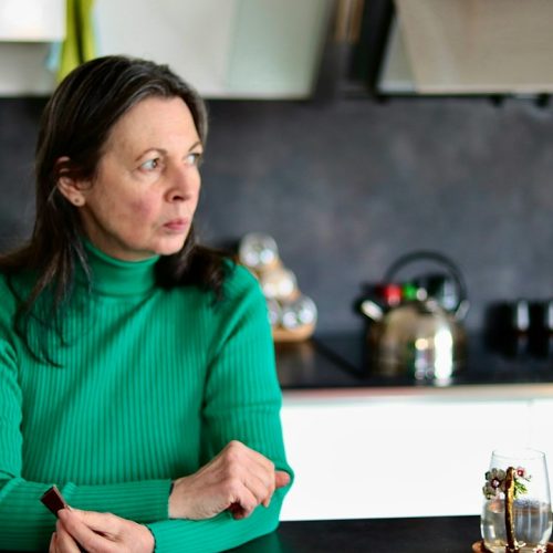 Woman sitting in her kitchen looking tired and thoughtful